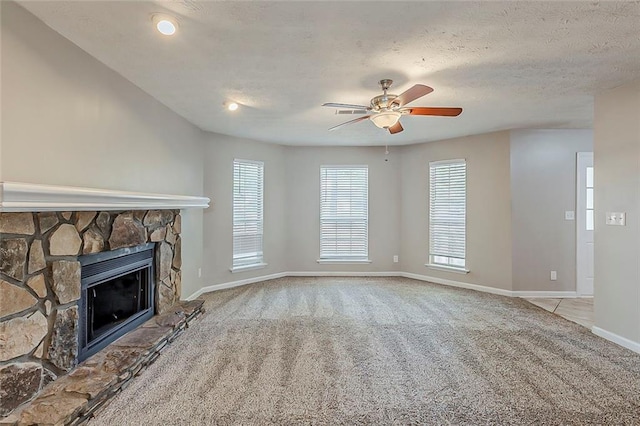 unfurnished living room with carpet, a fireplace, baseboards, ceiling fan, and a textured ceiling