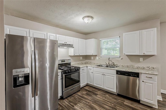 kitchen featuring stainless steel appliances, a sink, under cabinet range hood, dark wood finished floors, and white cabinetry