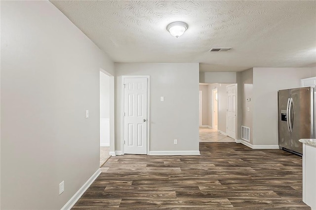 empty room featuring dark wood finished floors, a textured ceiling, and baseboards