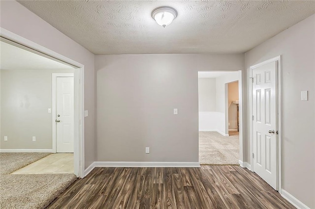 empty room featuring dark wood-style floors, baseboards, and a textured ceiling