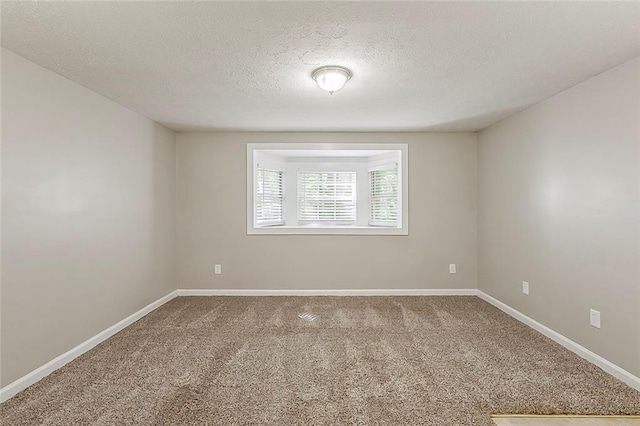 unfurnished room with a textured ceiling, carpet flooring, and baseboards