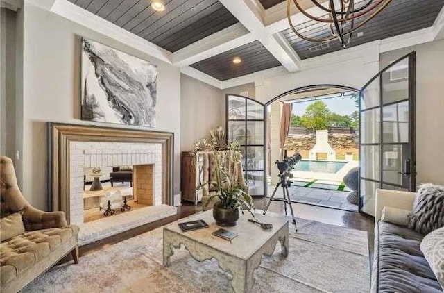 living area featuring coffered ceiling, beamed ceiling, crown molding, wood finished floors, and a fireplace