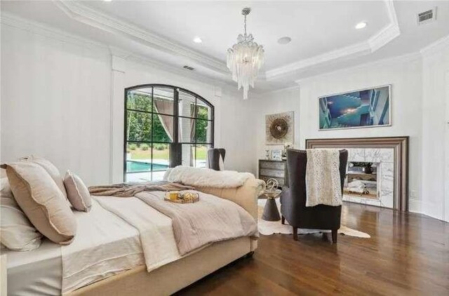bedroom featuring a tray ceiling, crown molding, dark wood finished floors, a chandelier, and recessed lighting