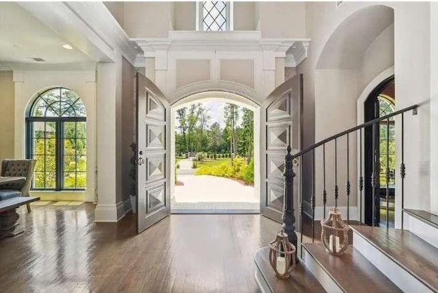 foyer entrance featuring wood finished floors, a high ceiling, baseboards, and stairway