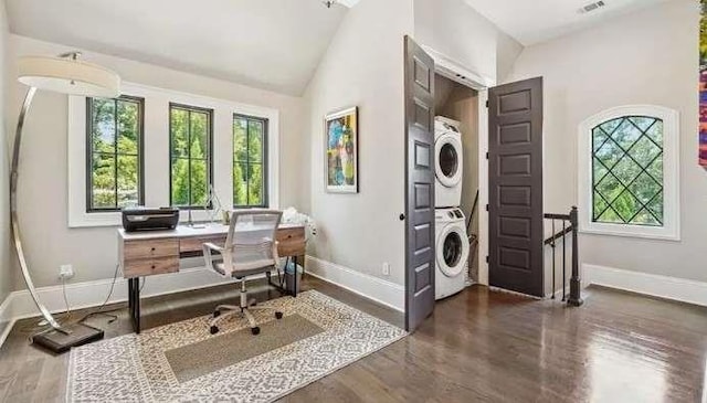 office space featuring estacked washer and dryer, baseboards, wood finished floors, and high vaulted ceiling