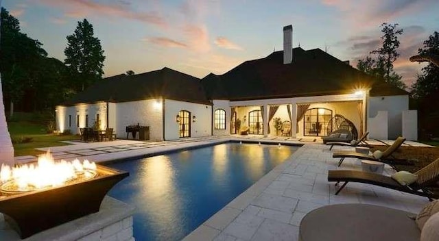 outdoor pool featuring a fire pit and a patio area