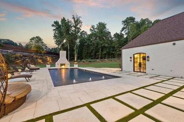 outdoor pool featuring a fireplace and a patio area