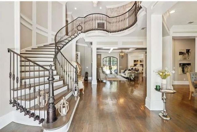 foyer with crown molding, a chandelier, wood finished floors, and stairway
