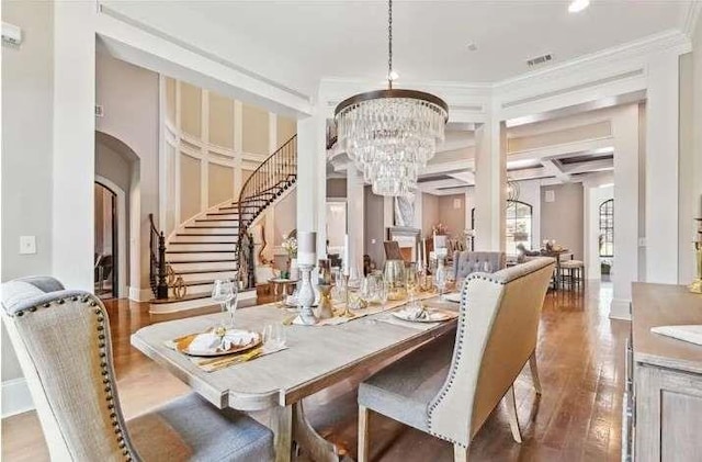 dining room with a chandelier, wood finished floors, stairway, crown molding, and arched walkways