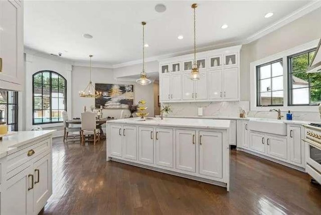 kitchen with a sink, crown molding, dark wood-type flooring, light countertops, and white cabinets