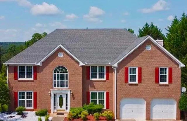 colonial-style house with brick siding, concrete driveway, a chimney, and a garage