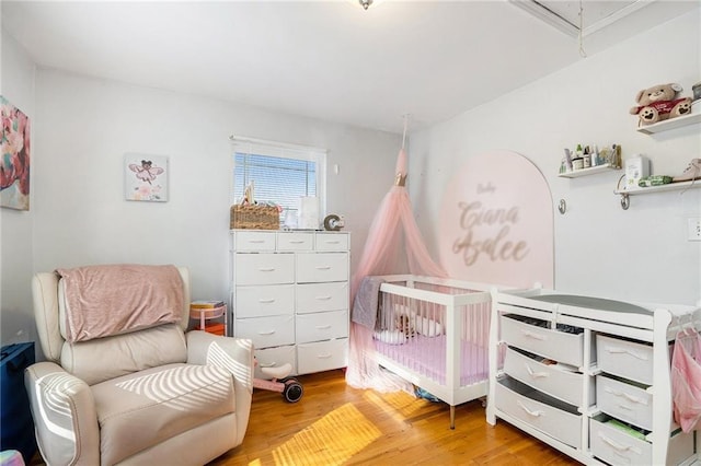 bedroom featuring a nursery area and light hardwood / wood-style floors