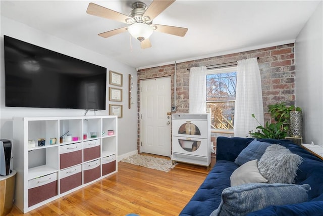 living room featuring ceiling fan, brick wall, and hardwood / wood-style flooring