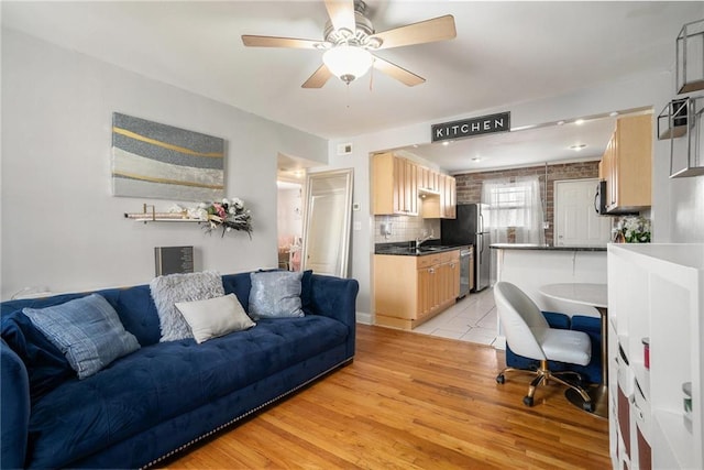 living room with light wood-type flooring, ceiling fan, and sink