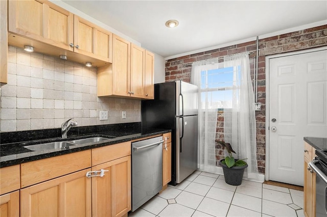 kitchen featuring stainless steel appliances, sink, light tile patterned floors, light brown cabinets, and dark stone countertops