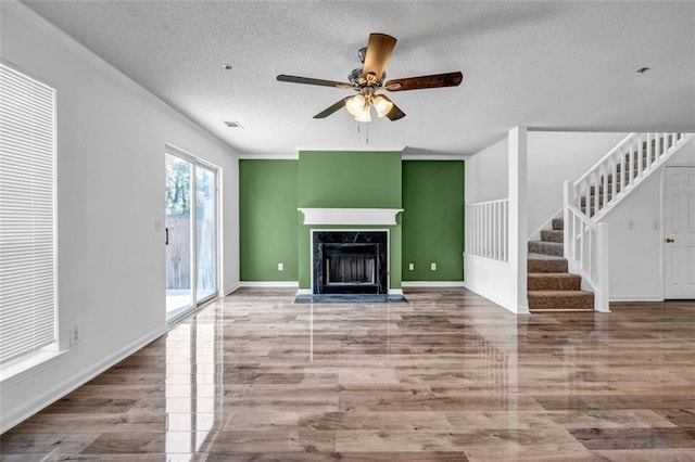 unfurnished living room with a high end fireplace, wood-type flooring, and a textured ceiling