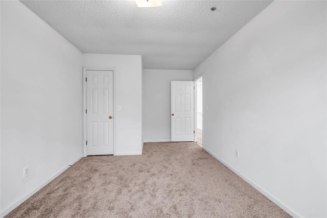 unfurnished room featuring a textured ceiling and light carpet