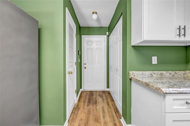 corridor with light hardwood / wood-style floors and a textured ceiling