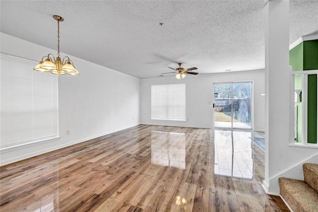 unfurnished living room with wood-type flooring, ceiling fan with notable chandelier, a textured ceiling, and crown molding