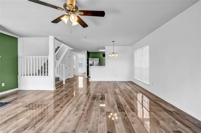 unfurnished living room with hardwood / wood-style floors and ceiling fan with notable chandelier