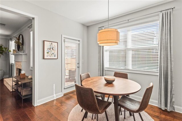 dining room with visible vents, a fireplace, baseboards, and wood finished floors