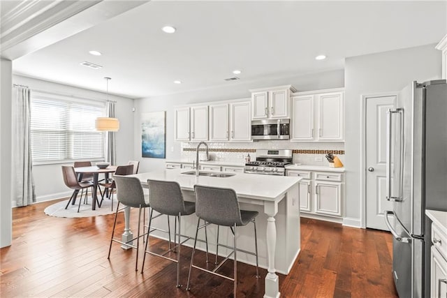 kitchen with dark wood-style flooring, a sink, visible vents, appliances with stainless steel finishes, and tasteful backsplash