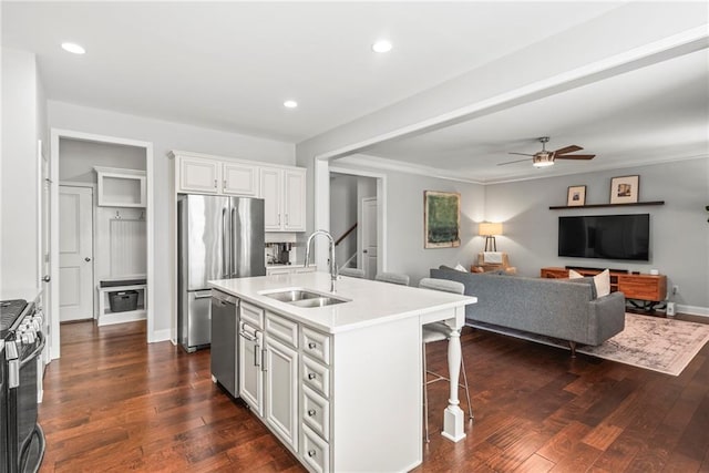 kitchen with dark wood-type flooring, a breakfast bar, a sink, white cabinets, and appliances with stainless steel finishes