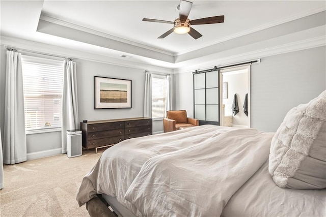 bedroom with carpet floors, a tray ceiling, a barn door, ornamental molding, and baseboards