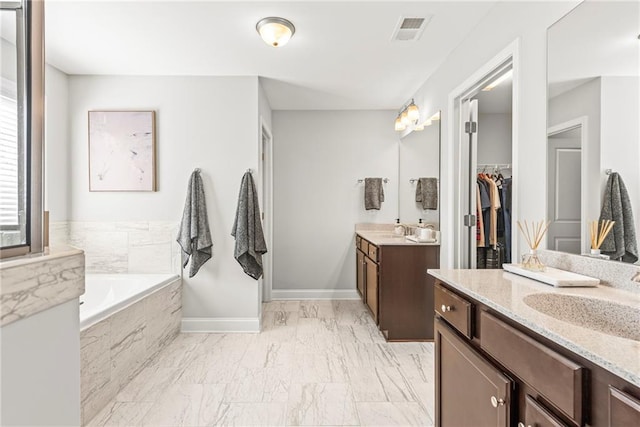 full bathroom featuring a bath, visible vents, two vanities, and a sink