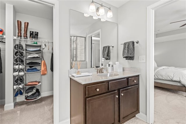 full bath with baseboards, a shower with door, ceiling fan, a spacious closet, and vanity