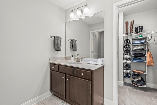 bathroom with marble finish floor, baseboards, and vanity