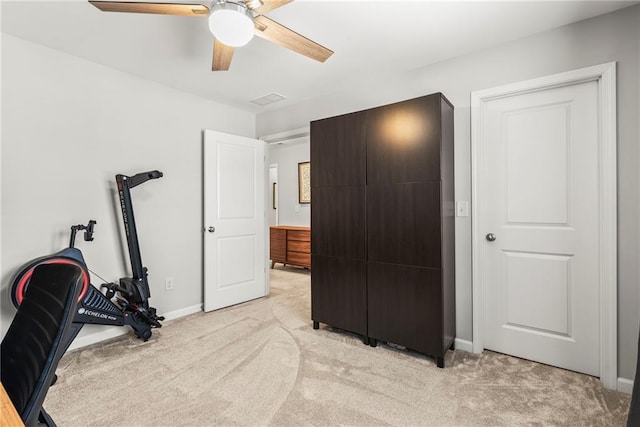 exercise room with light carpet, ceiling fan, and baseboards