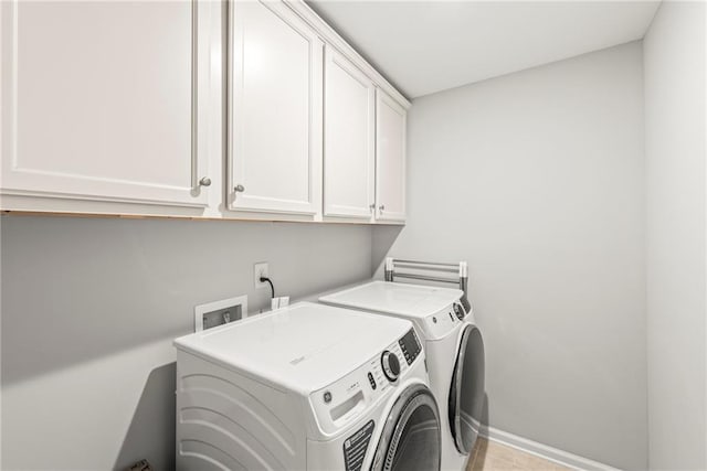 washroom featuring cabinet space, baseboards, and independent washer and dryer