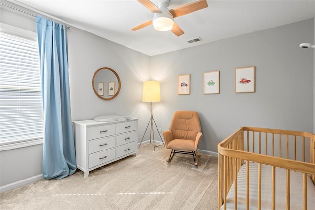 bedroom with light carpet, multiple windows, visible vents, and a crib