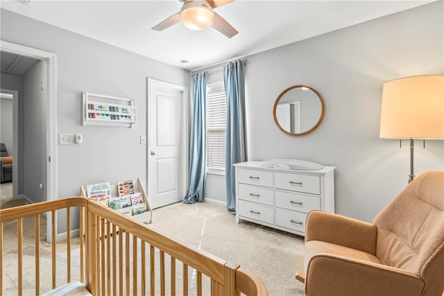 bedroom featuring attic access, a ceiling fan, light carpet, a crib, and baseboards