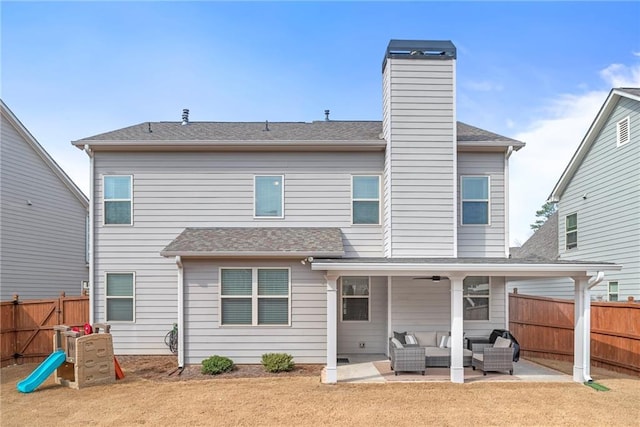 rear view of property featuring a playground, a chimney, an outdoor hangout area, a patio area, and a fenced backyard