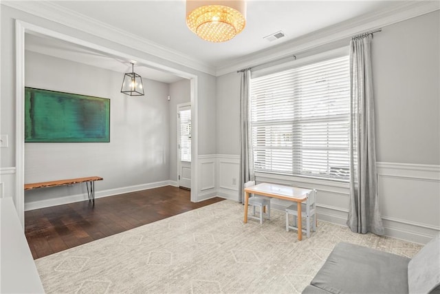 interior space featuring crown molding, visible vents, wood finished floors, and wainscoting