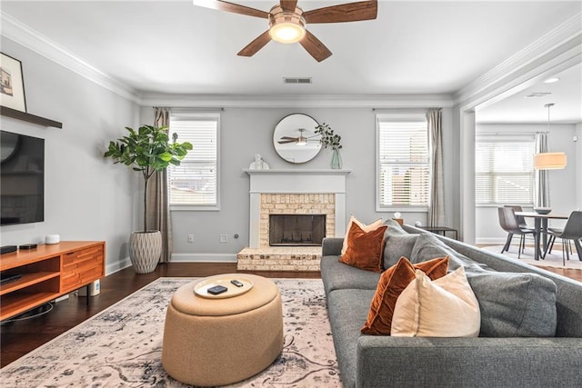 living room with ornamental molding, dark wood finished floors, visible vents, and a fireplace