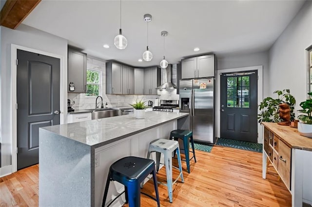 670 Parker Ave, Decatur, GA 30032 - kitchen featuring wall chimney range hood, a sink, stainless steel appliances, tasteful backsplash, and light wood finished floors