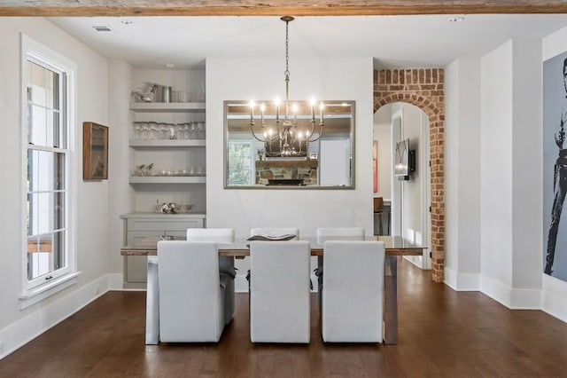 dining space with a chandelier, dark wood finished floors, arched walkways, baseboards, and built in features