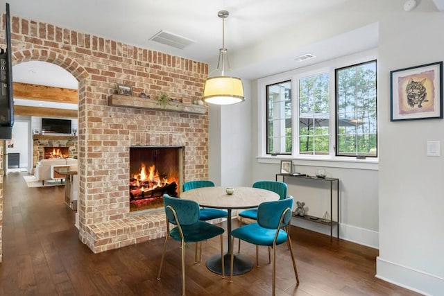 dining room with a brick fireplace, baseboards, and hardwood / wood-style flooring