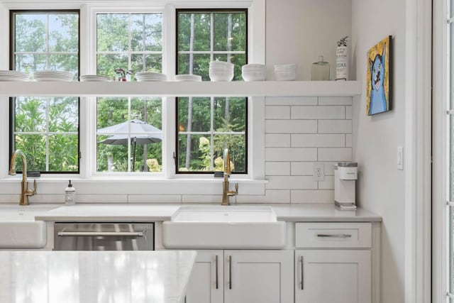 kitchen with a sink, dishwasher, decorative backsplash, and light countertops