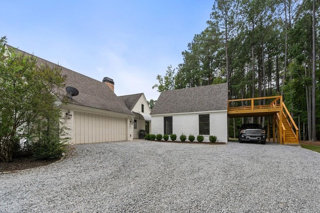 view of front of property with driveway, stairway, a carport, a garage, and a chimney