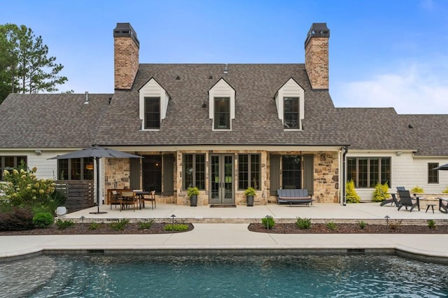 back of house with a chimney, stone siding, and a patio area