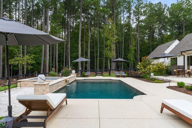 view of swimming pool featuring a patio, fence, a pool with connected hot tub, and view of wooded area
