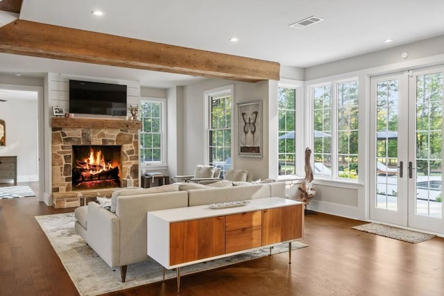 living area featuring a fireplace, french doors, dark wood-type flooring, healthy amount of natural light, and beamed ceiling