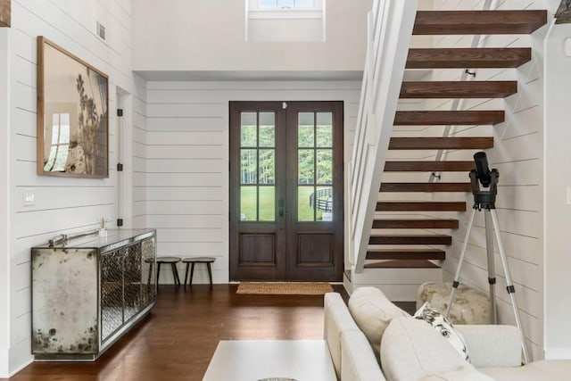 entryway featuring wood finished floors, wooden walls, french doors, and stairway