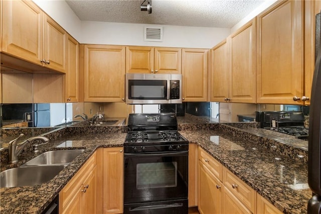 kitchen featuring dark stone countertops, sink, gas stove, and a textured ceiling