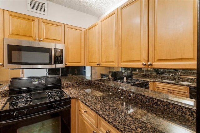 kitchen featuring black range with gas stovetop, sink, a textured ceiling, and dark stone countertops