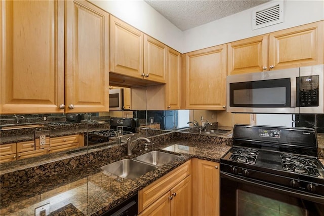 kitchen featuring dark stone countertops, sink, a textured ceiling, and black appliances